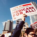 Sign in reds on white background that says Love It! Improve It! Medicare for All!