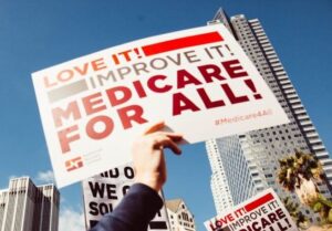 Sign in reds on white background that says Love It! Improve It! Medicare for All!