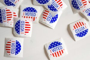 I Voted stickers in red, white, and blue scattered across a white surface