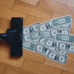 A pile of money being vacuumed off a wooden floor