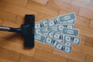 A pile of money being vacuumed off a wooden floor