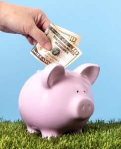 Hand putting 10 dollar bill in piggybank