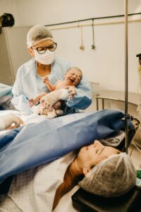 Doctor or nurse holding a baby after Cesarean delivery